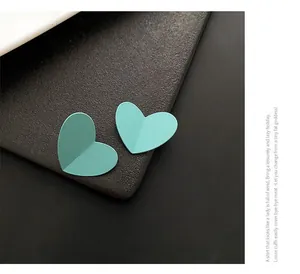 Macro view of matte mint green heart-shaped earrings with minimalist folding texture
