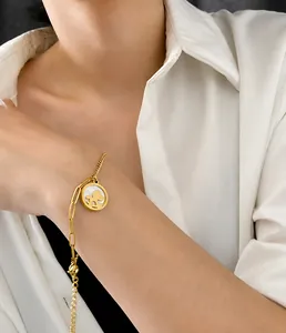 Detail von 18K vergoldetem Armband mit Bären-Anhänger und Muscheleinlage am Handgelenk