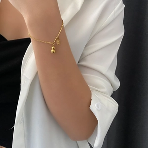 Golden gourd charm bracelet with lucky coin pendant on woman wrist in minimalist style