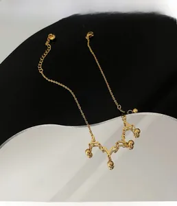 Detailed shot of golden crown anklet with geometric V-links and polished metal balls