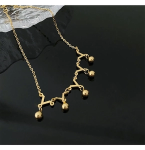 Detail of gold crown anklet with five beads and zigzag design on black surface