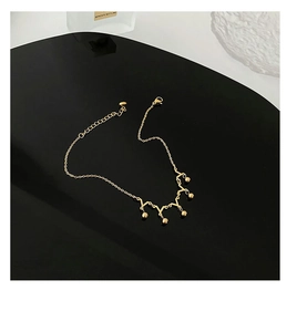 Detail of a gold crown-style anklet with small spheres on a premium black curved stand