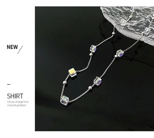 Detail of silver chain necklace featuring rainbow crystal beads on a sleek black background