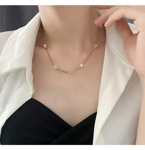 Detail of gold titanium steel necklace with crystal square beads on a model wearing a blazer