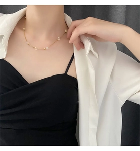 Close-up of a gold-tone crystal beaded necklace on a model with elegant layered outfit