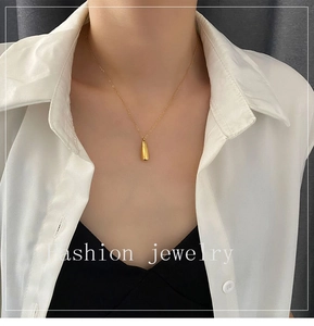 Collier pendentif goutte doré minimaliste porté par un mannequin sur une chemise blanche
