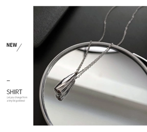 Détail du collier pendentif goutte d'argent sur miroir avec design moderne épuré
