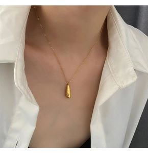 Vue détaillée du pendentif flacon de parfum en titane doré sur une chaîne fine