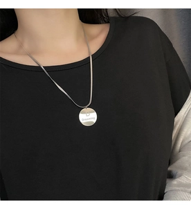 Détail de la chaîne serpent argentée avec pendentif rond lettre D Dreaming sur noir