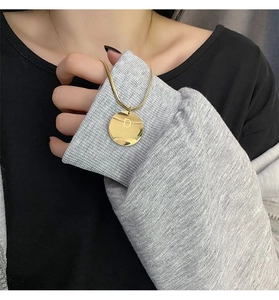 Détail du collier doré avec pendentif lettre D Dreaming et chaîne serpent fine