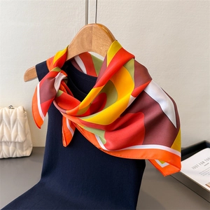 Gros plan d'un foulard en soie à motif géométrique sur un gilet bleu marine stylé