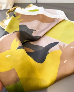Detail of silk-like satin square scarf with abstract animal pattern in mustard and grey