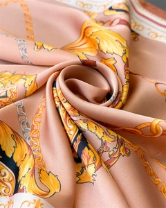 Macro detail of Baroque chain print silk scarf showing satin texture and gold floral patterns