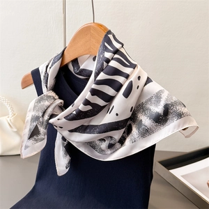 Détail d'un foulard en soie à motif zèbre noir et blanc sur un haut bleu marine
