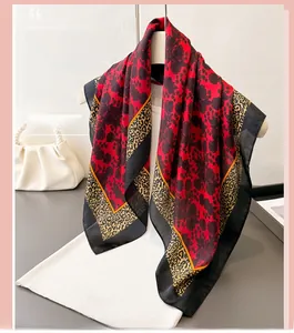 Detailed view of elegant red silk scarf with black rose pattern and leopard print trim