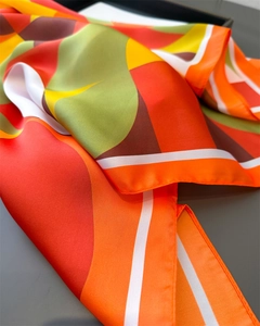 Gros plan d'un foulard en soie aux motifs géométriques et bordures cousues fines