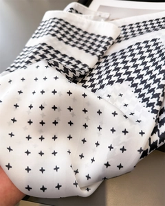 Gros plan sur le motif pied-de-poule et l'étoile géométrique d'un foulard en soie doux