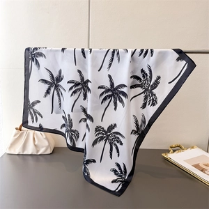 Detailed view of square silk scarf with black palm tree prints and rolled edges