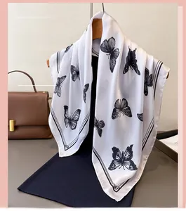 Close-up of elegant silk scarf with black butterfly prints and striped borders