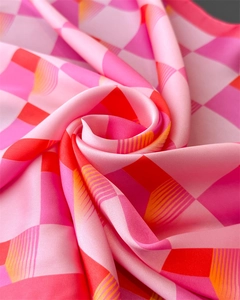Gros plan d'un foulard en soie au motif géométrique de losanges roses et rouges