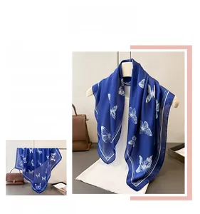 Detail of royal blue silk scarf with white butterfly prints and elegant linear borders