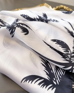 Macro shot of tropical palm leaf print on white satin fabric with elegant silk texture