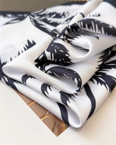 Detail of silk-like scarf featuring black palm tree prints and a smooth satin texture