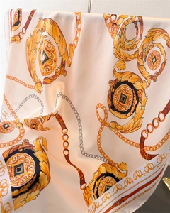 Close-up of luxury silk scarf with golden chain and baroque prints in beige