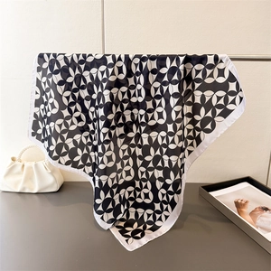 Detail of silk-like square scarf featuring black and white geometric floral patterns