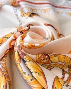 Detail of silk-like scarf with gold chain print folded into a rose shape for texture