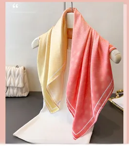 Detail of silk scarf with orange gradient, polka dots, and delicate print on a hanger
