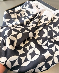 Close-up of geometric chain print silk scarf with luxury satin finish and draped texture
