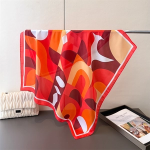 Détail d'un foulard en satin à motif géométrique rouge et orange avec une texture soyeuse