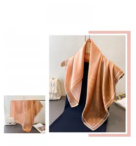 Detailed view of orange silk scarf featuring white polka dots and geometric patterns