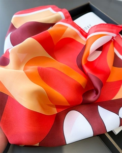 Détail d'un foulard en soie avec des motifs géométriques dans les tons rouge et orange