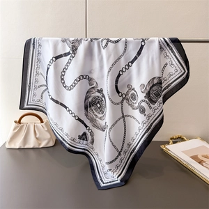Detail of elegant silk-like square scarf with chain print draped in a luxury setting