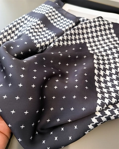 Détail macro du motif pied-de-poule et imprimés étoiles sur l'écharpe en satin noir