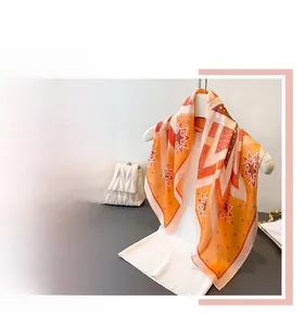 Detail of silk-feel scarf featuring orange geometric patterns and white star prints