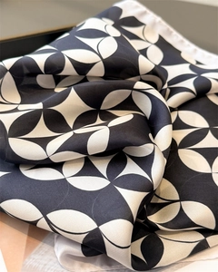Detail of silk-like satin scarf featuring black and white geometric floral print patterns