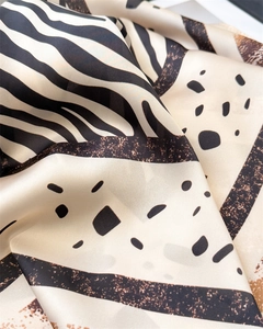 Gros plan d'un foulard en soie à motif zébré avec pois et texture satinée lisse