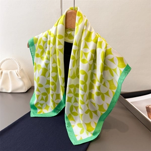 Elegant silk-like square scarf with green and yellow geometric clover print on a wooden hanger