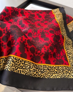 Detailed view of red silk square scarf with floral print and leopard print borders