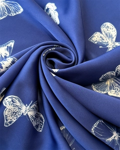 Detailed close-up showing silk-like fabric texture and white butterfly patterns on navy scarf
