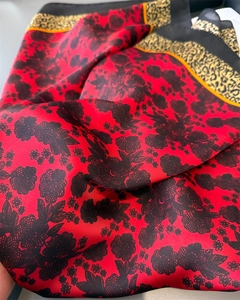 Detail of red silk scarf with vintage black floral patterns and leopard print borders