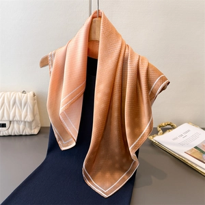 Elegant gradient orange silk scarf with white polka dots on a wooden hanger with bag