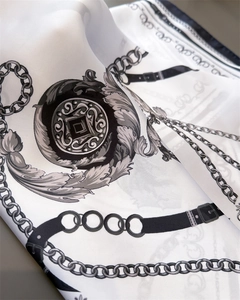 Macro view of luxurious chain and belt print silk scarf showing satin fabric texture