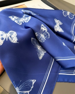 Detail view of royal blue silk scarf with white butterfly prints and soft fabric folds