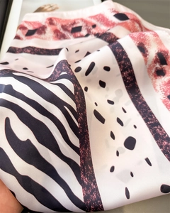 Gros plan d'un foulard soyeux avec motif zèbre, pois et rayures roses douces