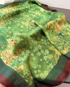 Detail of silk-feel scarf with green floral bamboo prints and contrast borders