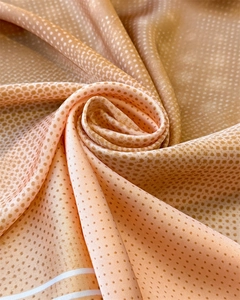 Detailed view of silk scarf fabric showing orange gradient colors and polka dot texture